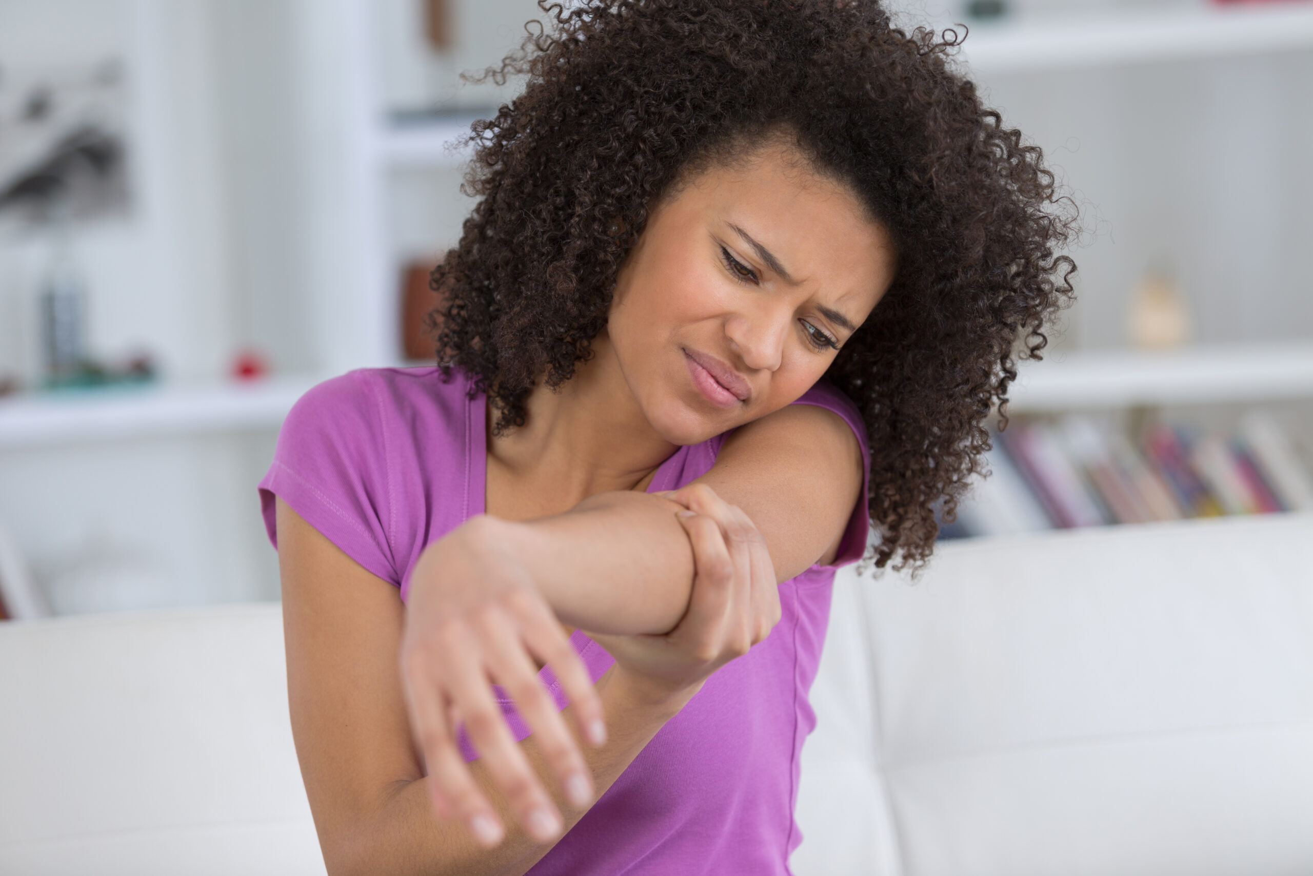 Person experiencing arm pain requiring chiropractic treatment in Costa Mesa